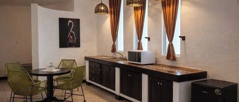 Una cocina compacta con comedor, que incluye un microondas, armarios y un refrigerador pequeño.