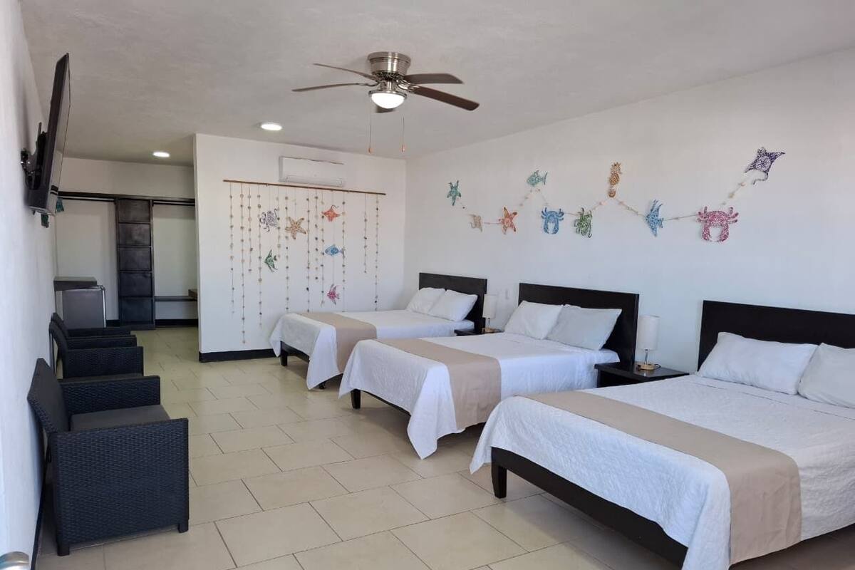 A hotel room with three single beds, a ceiling fan, and a decorative wall hanging.
