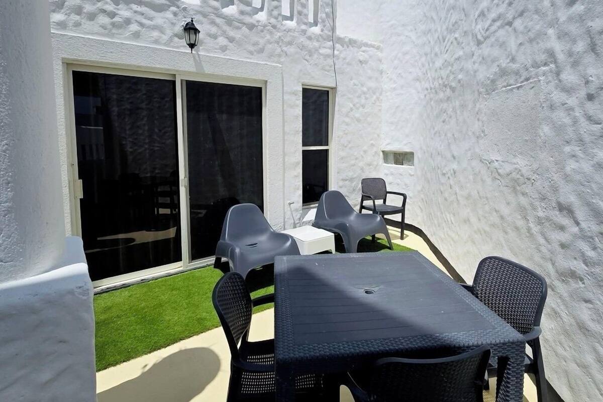 A white building with a patio area featuring a table and chairs.