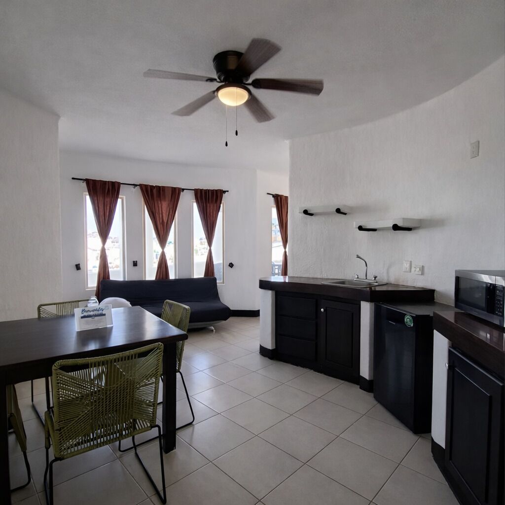 A compact kitchen with a dining area, a ceiling fan, and a view through the windows.