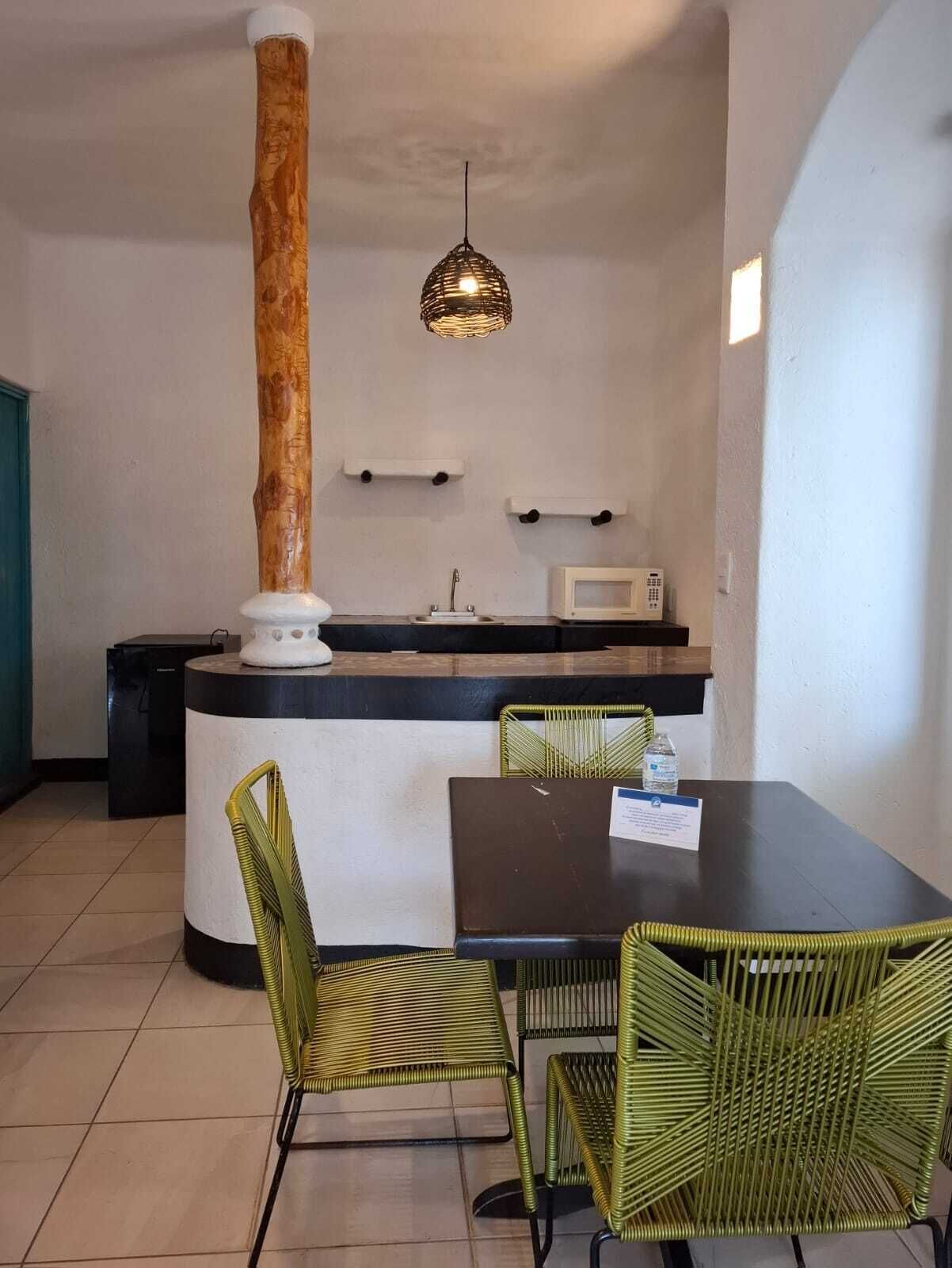 A compact kitchen with a central island, a dining table with chairs, and a hanging light fixture.