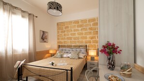 A bedroom with a bed, bedside lamps, a nightstand, a vase with flowers, and a plate of pastries. - Villa Lilibeth, A private villa with private swimming pool in San Vito Lo Capo (San Vito Lo Capo)