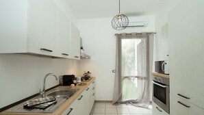 A compact kitchen with a sink, stove, and microwave. It features white cabinetry, a wooden countertop, and a pendant light. - Villa Lilibeth, A private villa with private swimming pool in San Vito Lo Capo (San Vito Lo Capo)