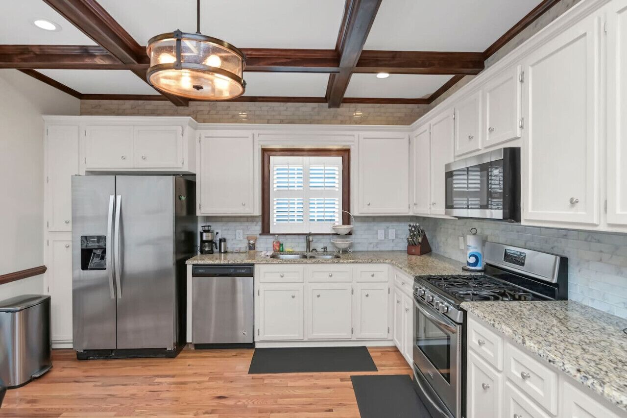 A modern kitchen with white cabinets, stainless steel appliances, and a granite countertop.