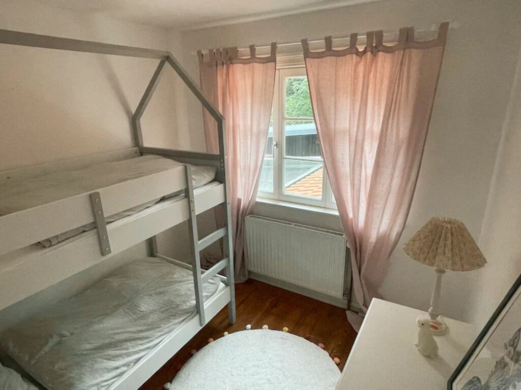 Habitación con literas, ventana, radiador y lámpara.