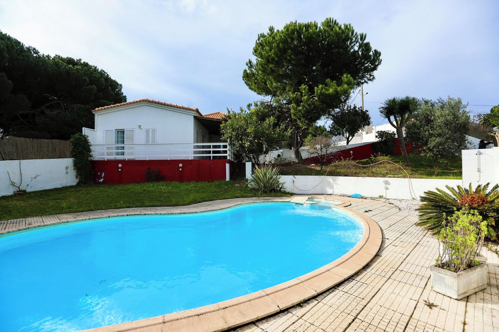 A swimming pool with a curved edge, surrounded by a paved deck.