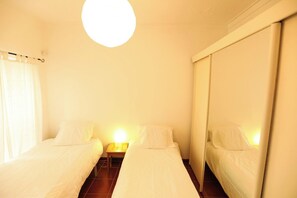 A room with two beds, a nightstand, and a mirror.