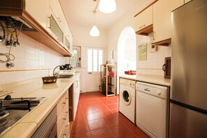 A kitchen with a stainless steel refrigerator, a washing machine, and a sink.
