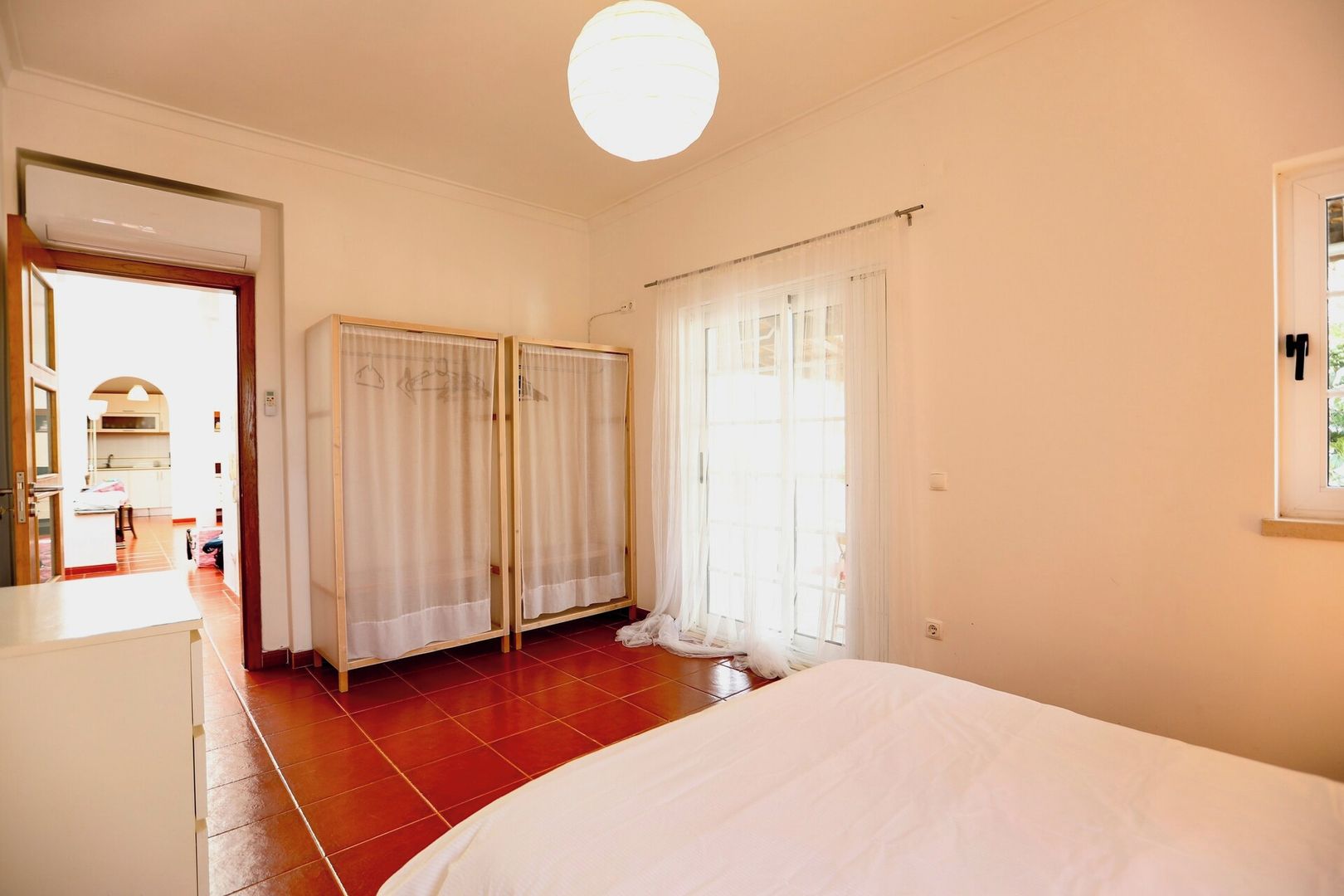 Un dormitorio con cama, armario y ventana con cortinas.