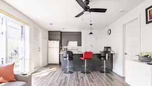 Eine moderne Küche mit einer zentralen Kochinsel, Barhocker und einem Deckenventilator.