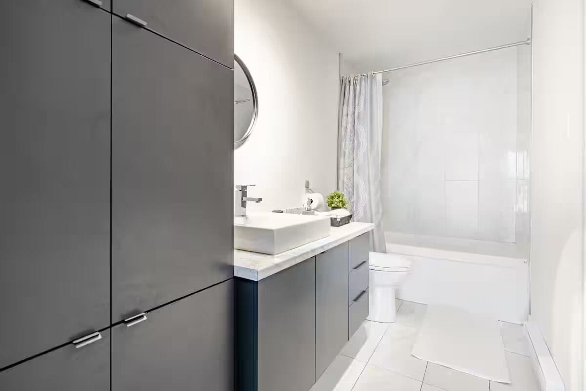 Une salle de bain moderne avec un grand miroir, un lavabo blanc et un espace douche.