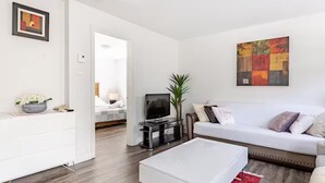 Ein modernes Wohnzimmer mit einem weißen Sofa, einem Flachbildfernseher, einem weißen Couchtisch und einem roten Teppich.