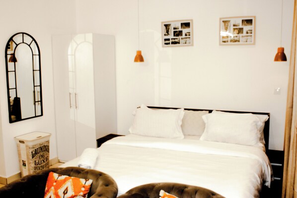 A bedroom with a bed, a wardrobe, a mirror, and a small table.