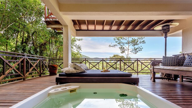 Un jacuzzi en una terraza de madera con vista al océano.
