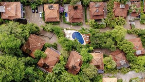 Vista aérea de una zona residencial con varias casas, una piscina y abundante vegetación.