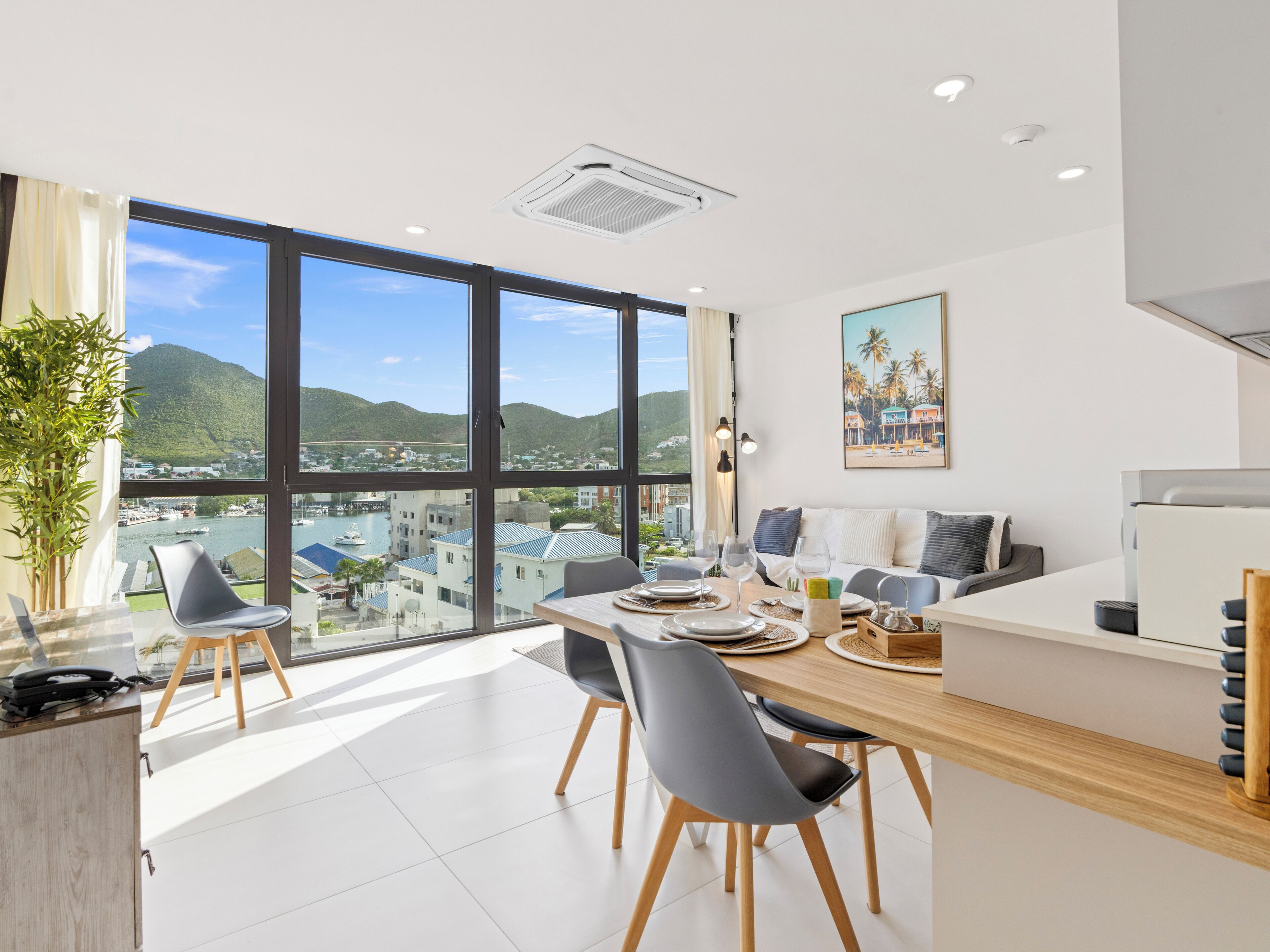 Un moderno comedor con un ventanal grande que ofrece vistas a un paisaje urbano y colinas.