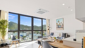 A modern dining area with a large window overlooking a cityscape and hills. - A123 -  1 bedroom with paradise view (Sint Maarten)