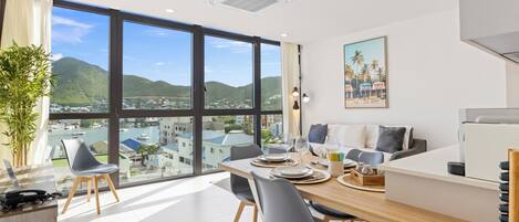 Un moderno comedor con un ventanal grande que ofrece vistas a un paisaje urbano y colinas.
