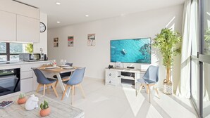 A modern kitchen with a dining area, a flat-screen TV, and a large window with a view of the sea. - A123 -  1 bedroom with paradise view (Sint Maarten)