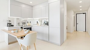 A modern kitchen with white cabinetry, a wooden dining table, and a white chair. - B201 - Wonderfull Apartment with terrasse (Sint Maarten)