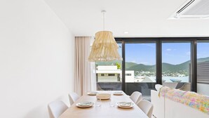 A dining area with a wooden table, white chairs, and a hanging light fixture. - B201 - Wonderfull Apartment with terrasse (Sint Maarten)