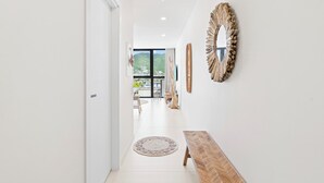Un pasillo moderno con un banco de madera, un tapete redondo tejido y un espejo decorativo.