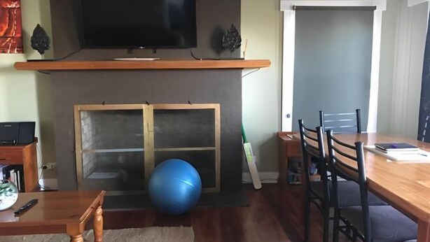 A living room with a fireplace, a television mounted above it, a dining table with chairs, and a blue exercise ball. - Beachend Bicheno (Bicheno)