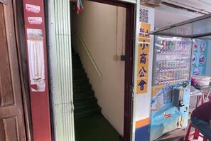A staircase leading to a room with a vending machine and a sign with Chinese characters. - Pelangi Capsule Hostel (Johor Bahru)
