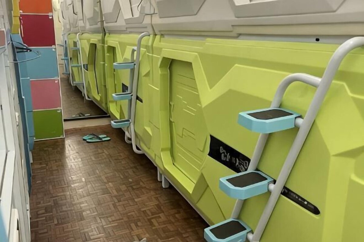 A row of green massage chairs with footrests and a wooden floor.