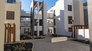 A modern residential building with a central courtyard, multiple balconies, and a minimalist design.
