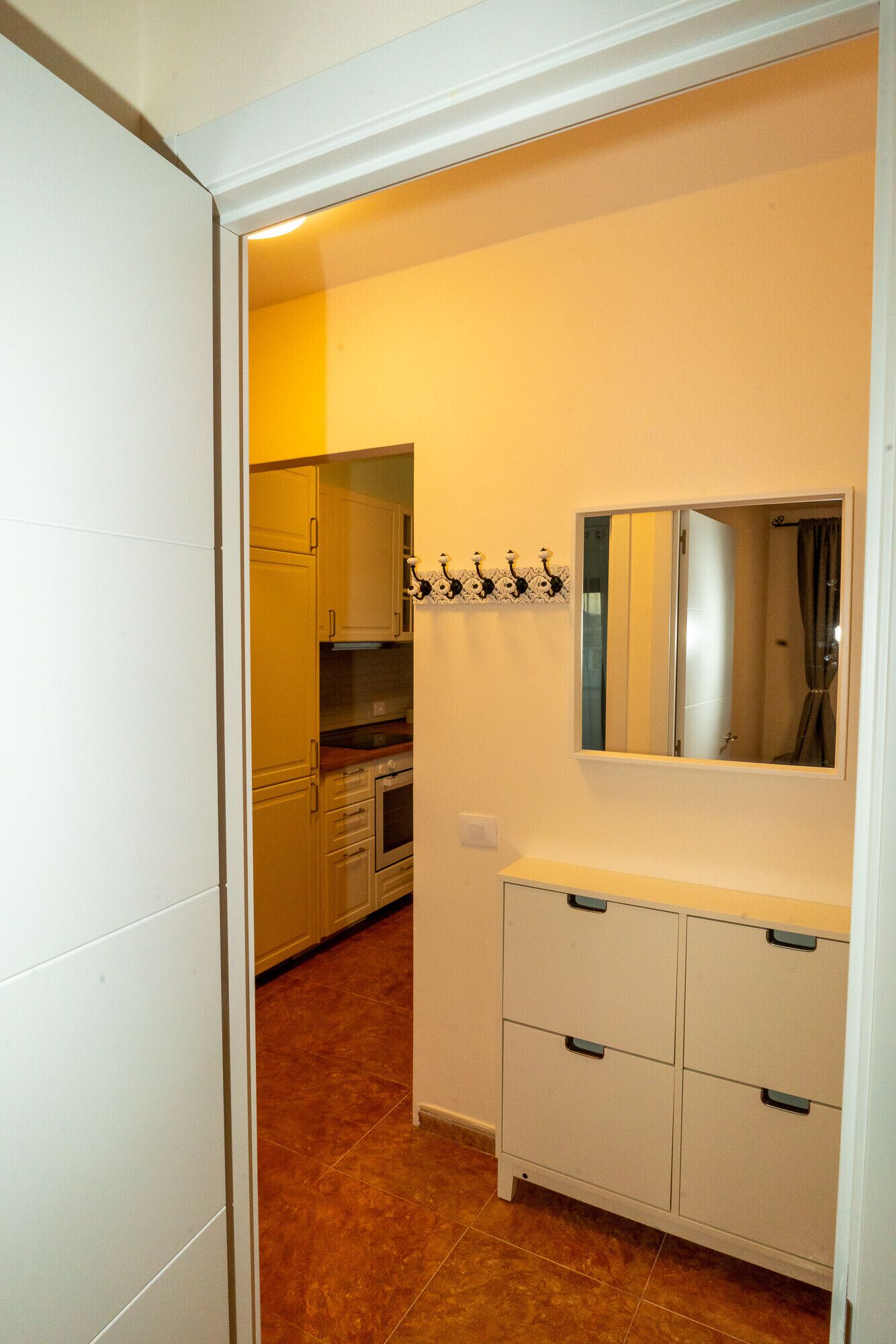 A narrow hallway leading to a kitchen with cabinets and a countertop.