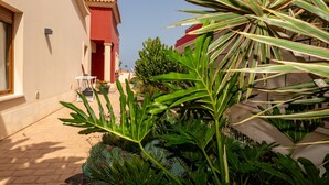 A courtyard with a red building, a white table, and various plants.