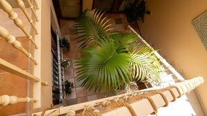 A balcony with a wooden balustrade, potted plants, and a view of a building with a tiled floor.