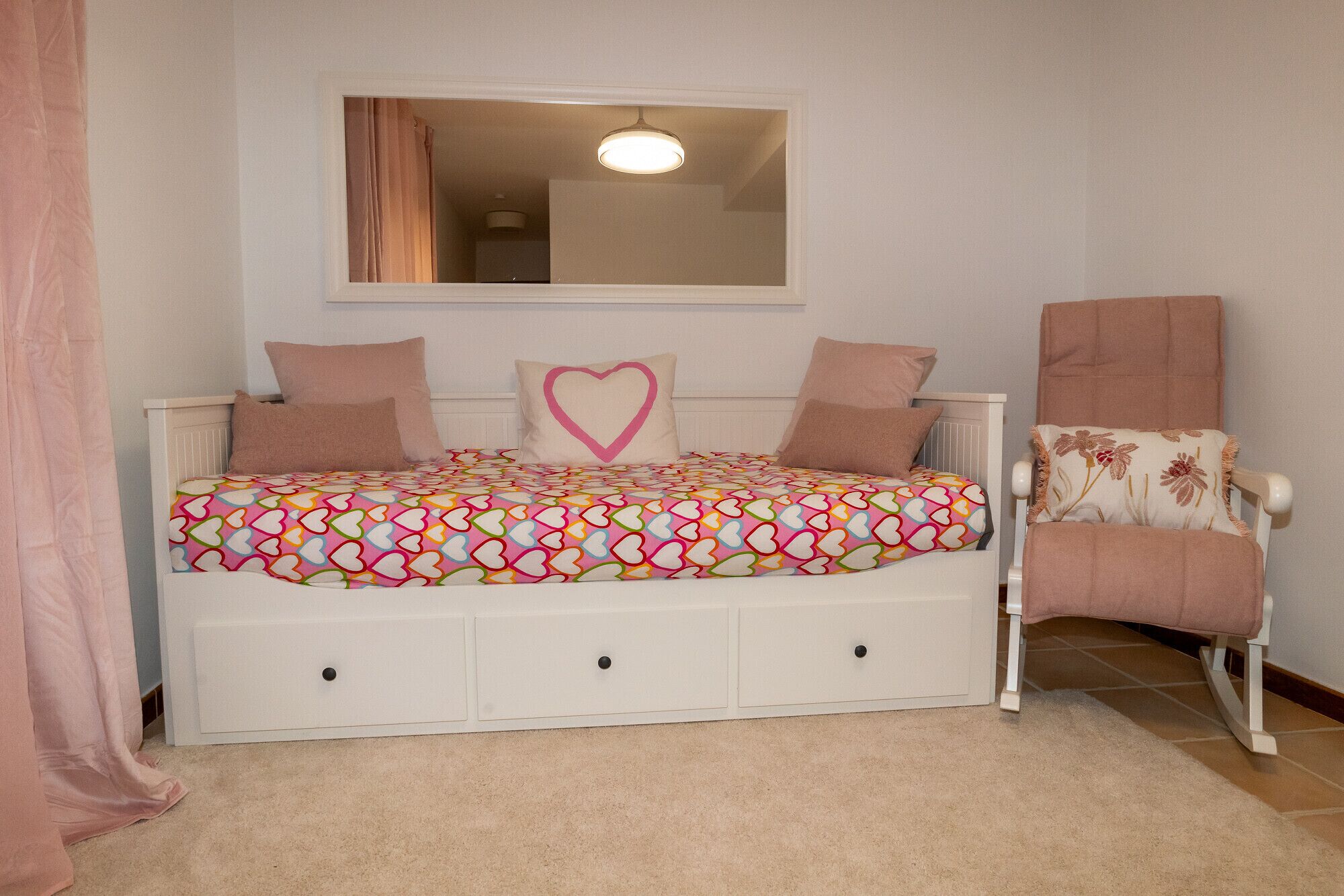 Une chambre à coucher avec un lit, une chaise et un miroir au mur.