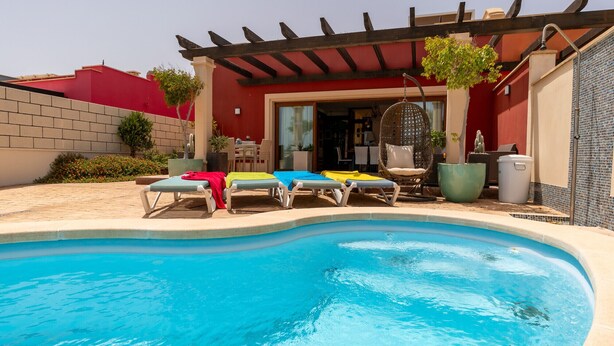 A pool area with lounge chairs and a pergola.