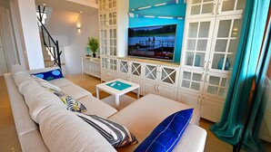 Ein modernes Wohnzimmer mit einer Couch, einem Couchtisch und einem an einem weißen Schrank montierten Fernseher.