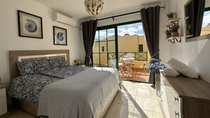 A bedroom with a bed, a balcony with a table and chairs, and a view of the outside. - Casa Garza – Castillo Mar 100m from the oceanfront (Caleta de Fuste)