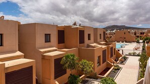 Un resort moderno con varias edificaciones, piscina y vista a la montaña.