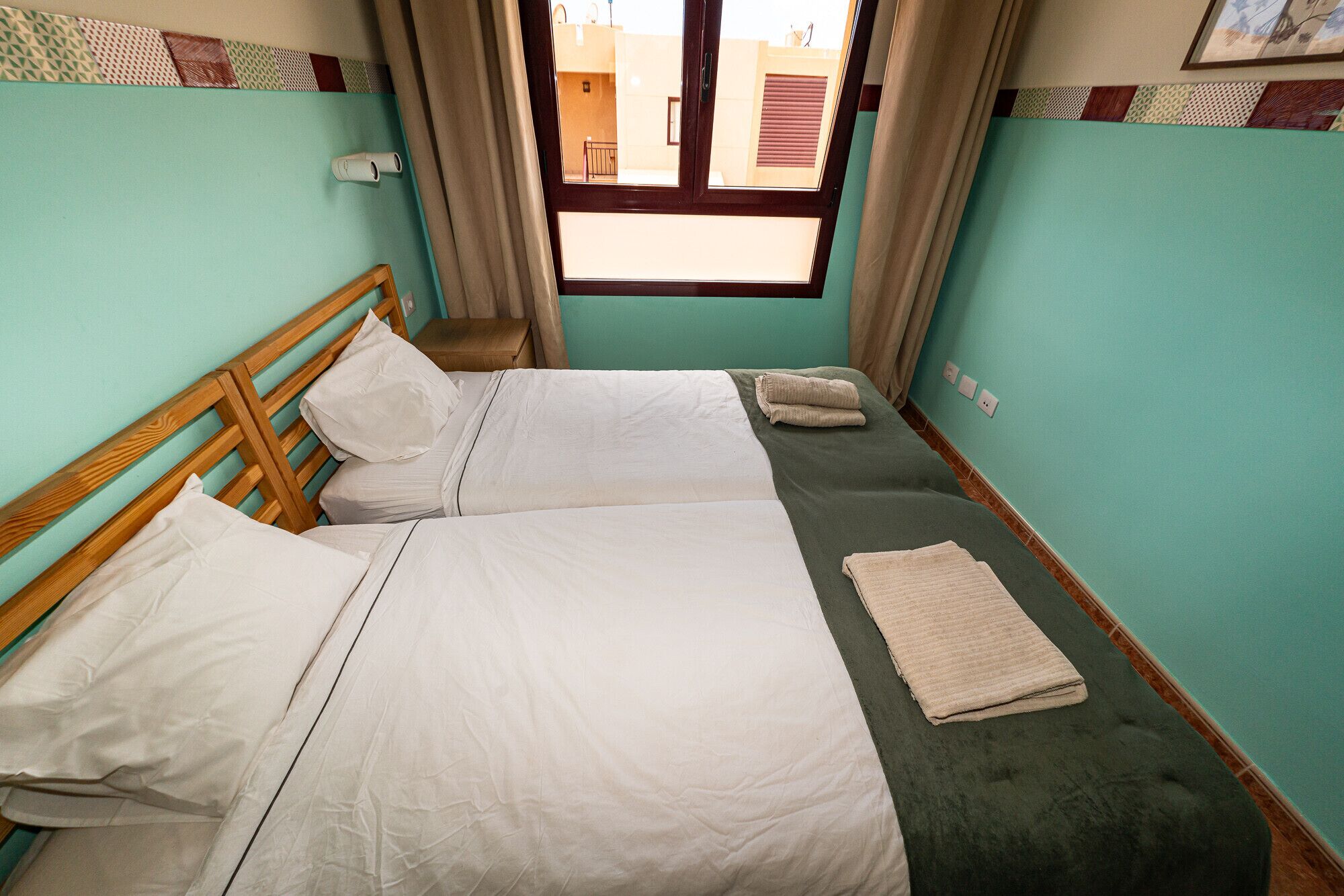 Une chambre double avec deux lits, une fenêtre et une petite table de chevet.