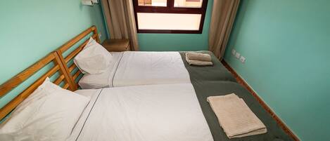 Une chambre double avec deux lits, une fenêtre et une petite table de chevet.
