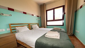 Una cama doble con cabecera de madera, una mesita de noche y una ventana con cortinas.
