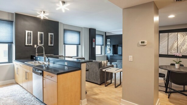 A modern kitchen with a central island, built-in appliances, and a dining area with a table and chairs.