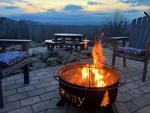 A fire pit with a visible brand name, surrounded by outdoor furniture and a scenic view of mountains. - Shenandoah Hideaway (Page County)