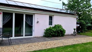 A single-story house with a patio, a table with chairs, and a bicycle parked outside. - Beautiful Self Contained Cottages in Westbury (Trowbridge)