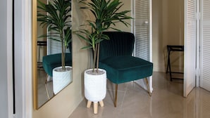 A modern interior with a teal sofa, two potted plants, a large mirror, and a wardrobe with sliding doors. - 15min to Ocho Rios-Family sized 2bed/2bath-Pool-BBQ Grill-100Mbps-Gated Complex (Drax Hall)