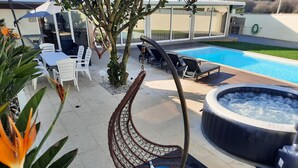 Ein Poolbereich mit Whirlpool, Liegestühlen und einer Pergola.