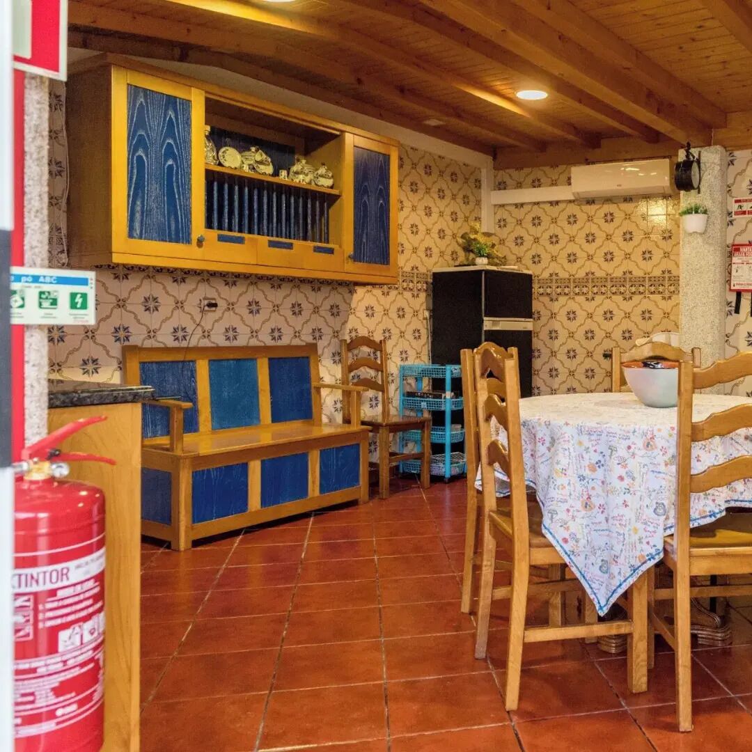 Un coin repas au style rustique, avec des meubles en bois, un sol carrelé et un papier peint à motifs.
