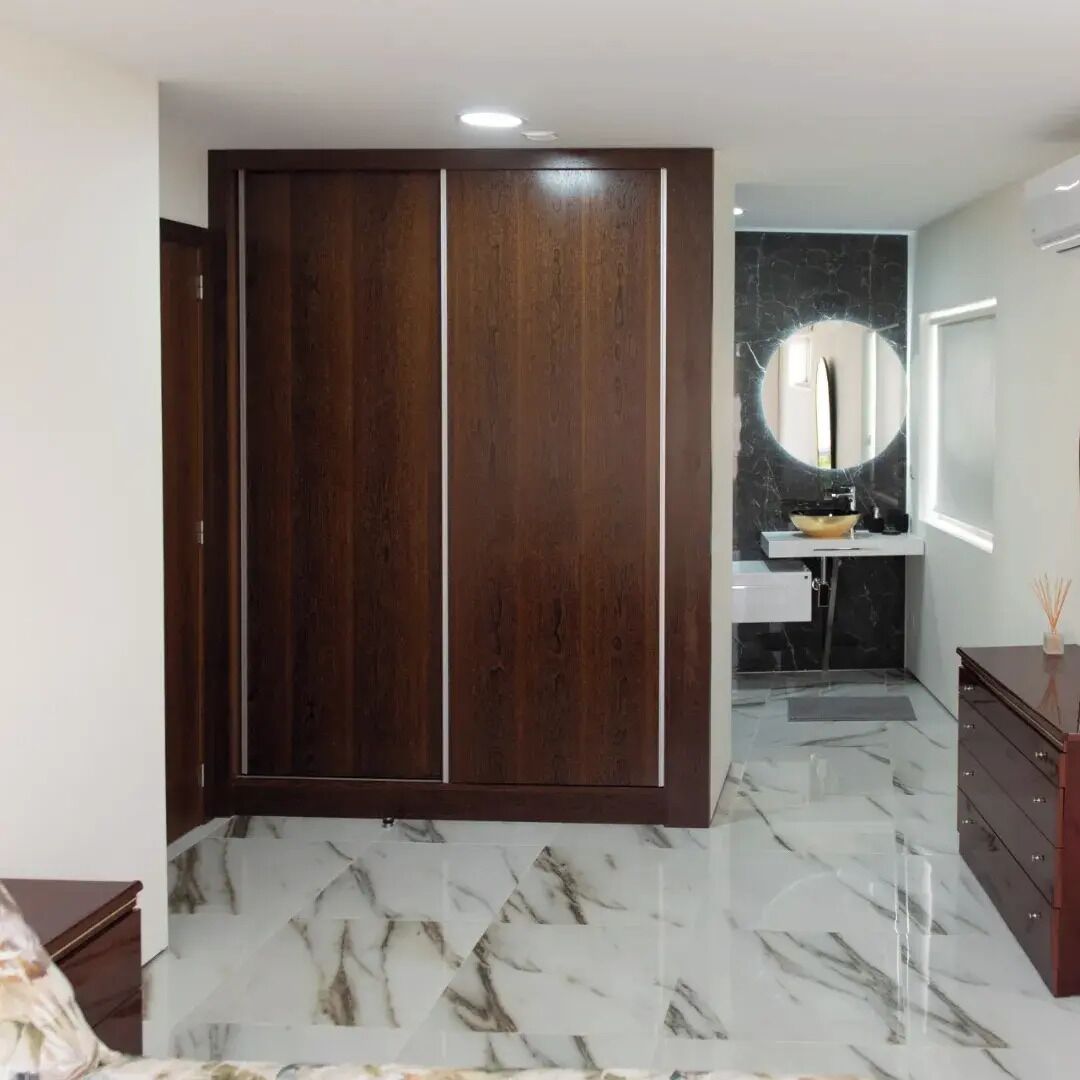 Un baño moderno con piso de mármol, un armario de madera, un lavamanos con encimera de mármol negro y un espejo grande.