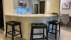 Una cocina moderna con una isla central, electrodomésticos de acero inoxidable y taburetes de bar.