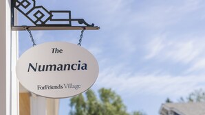 Un cartel que dice 'The Numancia For Friends Village' con un cielo despejado al fondo.